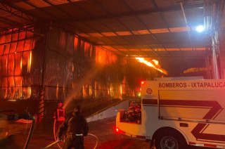 Bomberos trabajan para contener el incendio en la fábrica de telas