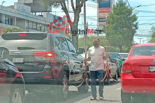 El hombre de 60 años pasa en medio de los automóviles cada semáforo vendiendo percheros.