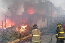 Vivienda en La Magdalena Ocotitlán ardiendo mientras bomberos combaten el incendio